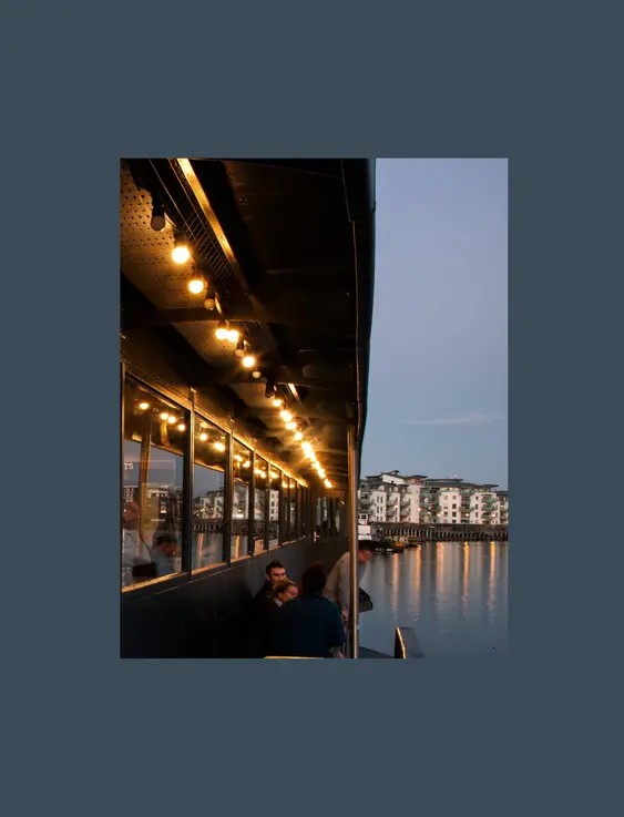 Picture of people sitting on the balcony of grain barge on Bristol harbour.