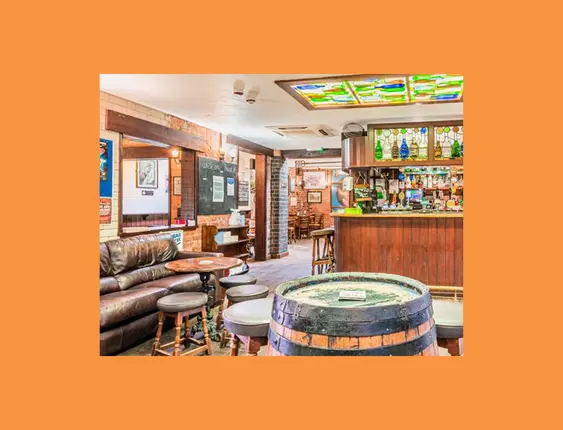 Warm pub interior with a wooden bar, stained glass features, and comfortable seating.