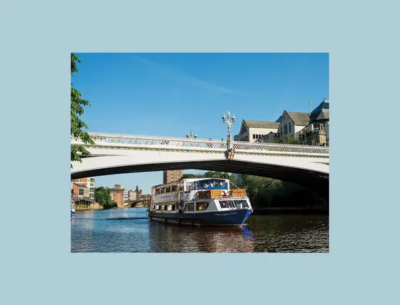 York city cruise going under a white bridge on a sunny day.