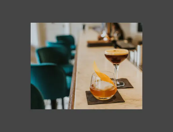 An old fashioned and espresso martini cocktail on a bar top.