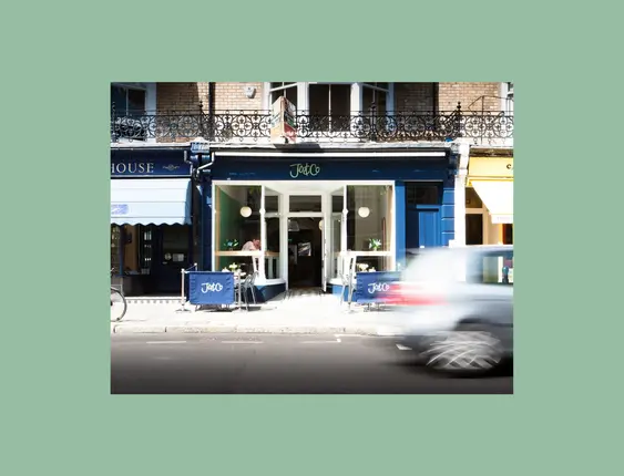 Restaurant front with a blue sign and chairs and tables outside