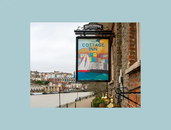 pub sign that says "the cottage inn" with a view of bristol in the background
