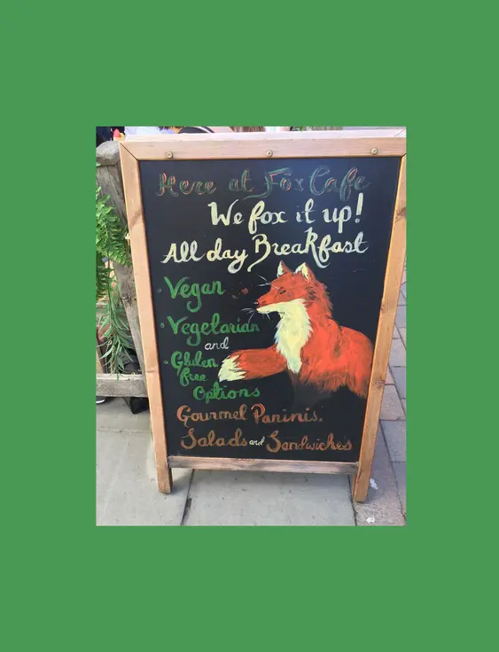 Chalkboard menu at Fox Café advertising vegan, vegetarian, and gluten-free options, decorated with a painted fox.