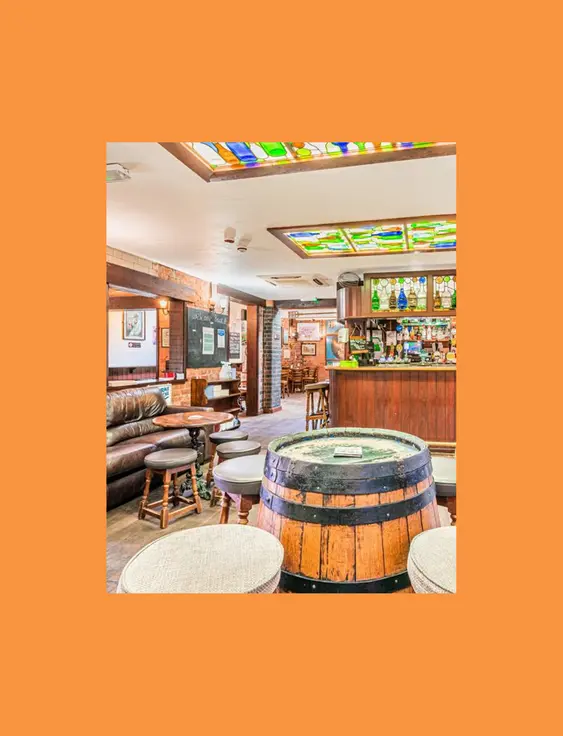 Warm pub interior with a wooden bar, stained glass features, and comfortable seating.