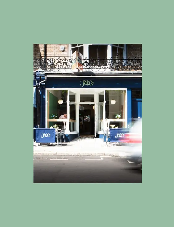 Restaurant front with a blue sign and chairs and tables outside